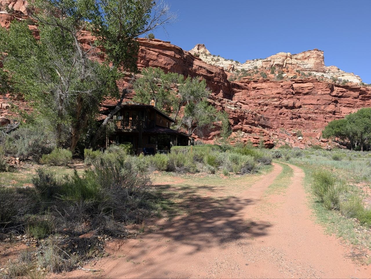 A small cabin tucked below red canyon walls and cottonwoods near Boulder, Utah