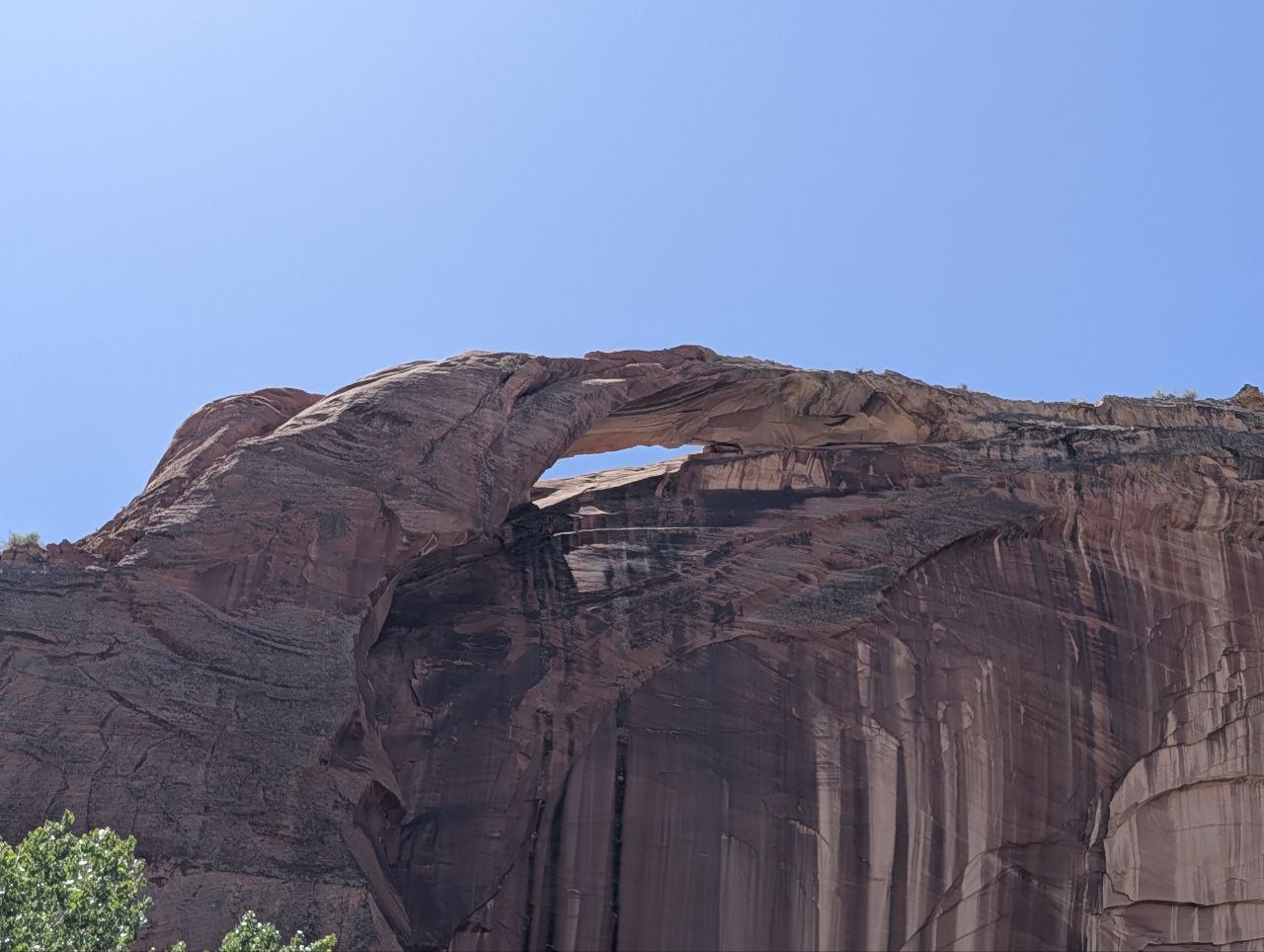 A natural arch window high in a red sandstone wall
