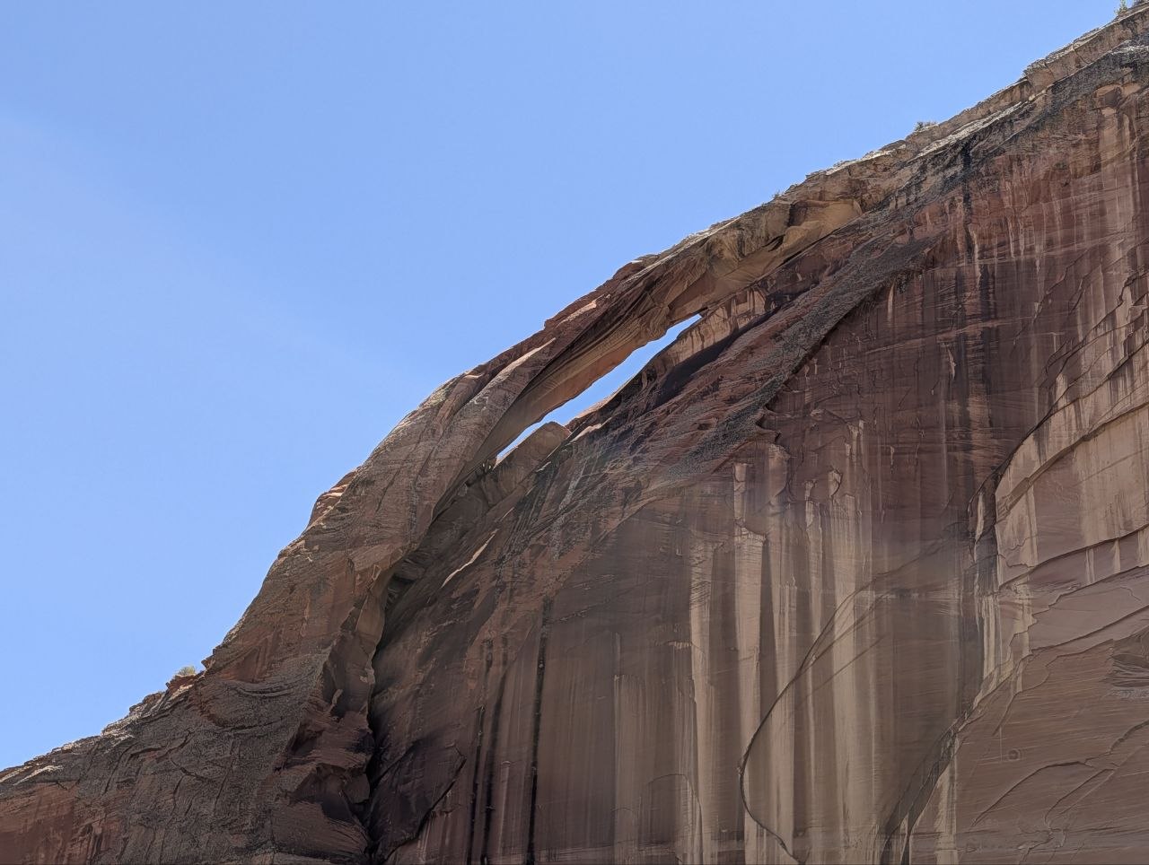 High natural sandstone arch cut into a red cliff face