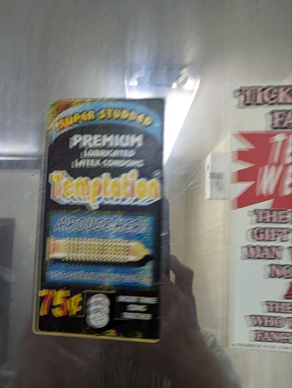A blurry vintage-style bathroom vending machine sticker advertising Tempter latex condoms