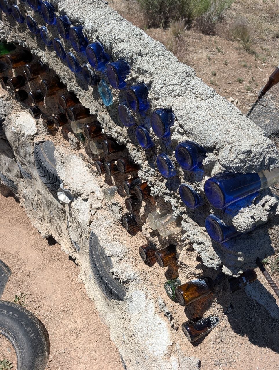 Close view of blue and brown glass bottles embedded in an Earthship wall