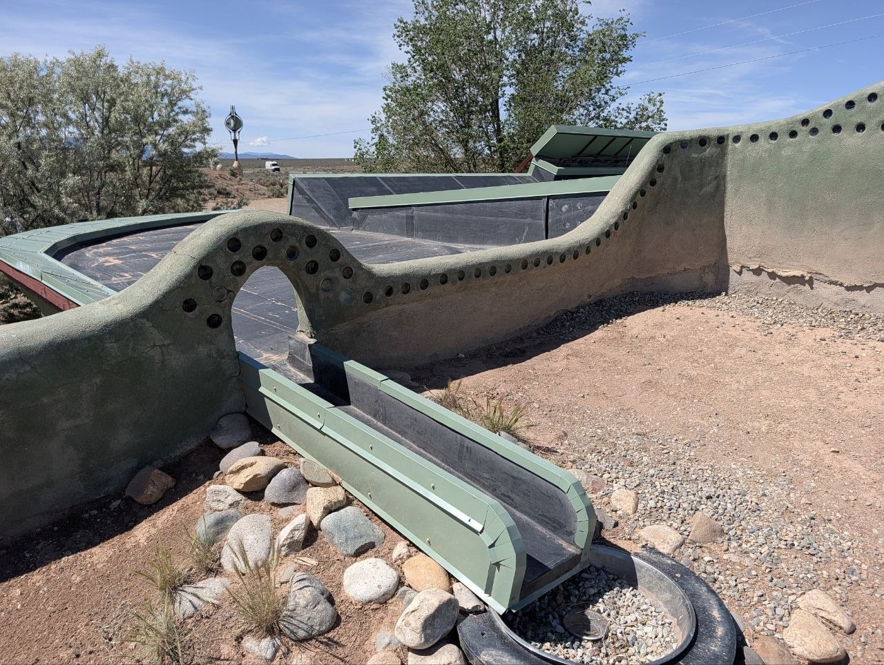 Earthship roof and water-channel detail with curved walls and dark collection surfaces